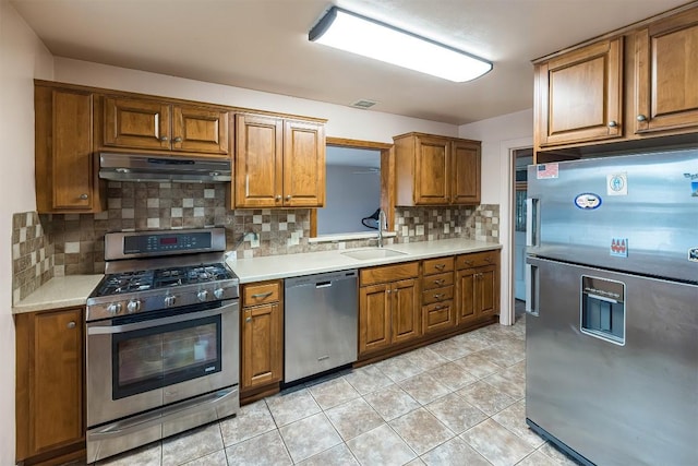 kitchen with light tile patterned flooring, stainless steel appliances, tasteful backsplash, and sink