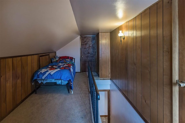 carpeted bedroom featuring wood walls and lofted ceiling