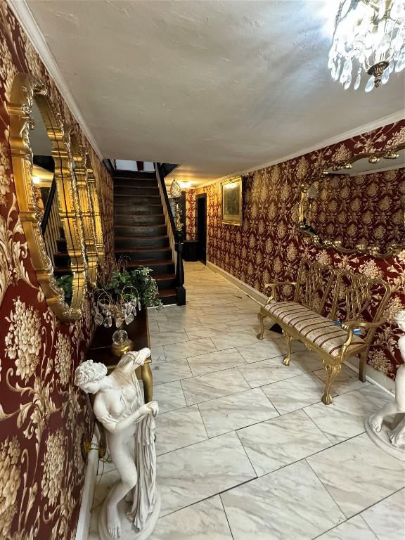 corridor with an inviting chandelier and crown molding