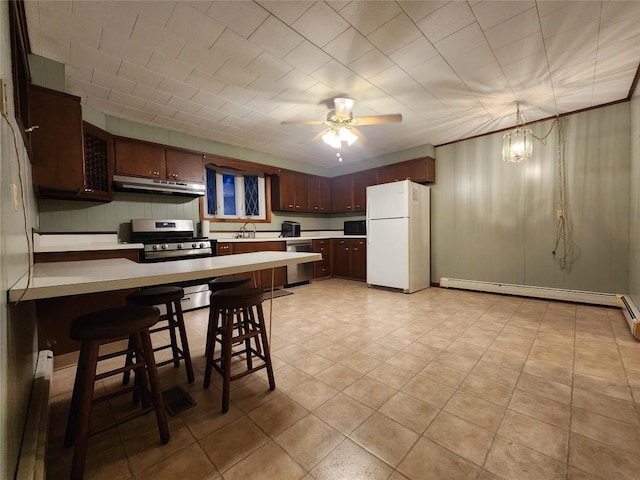 kitchen featuring kitchen peninsula, appliances with stainless steel finishes, a kitchen breakfast bar, baseboard heating, and sink