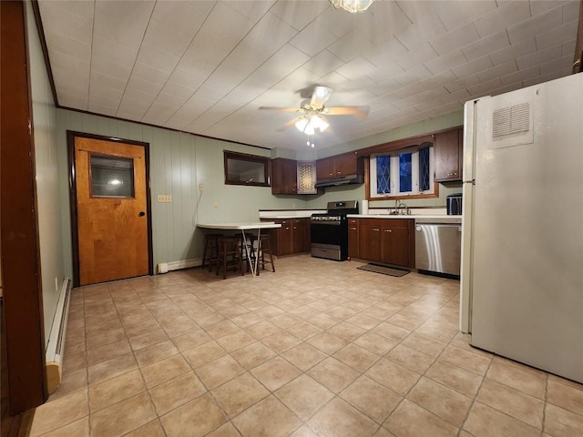 kitchen featuring wood walls, dark brown cabinets, ceiling fan, and appliances with stainless steel finishes