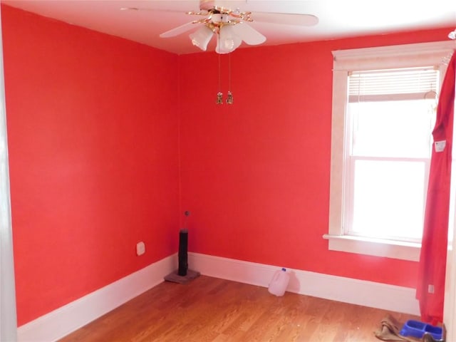 laundry area with ceiling fan, a wealth of natural light, and wood-type flooring