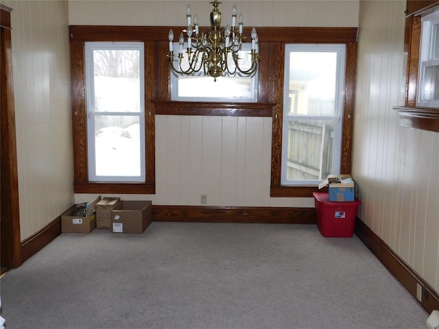 unfurnished dining area with a notable chandelier and carpet