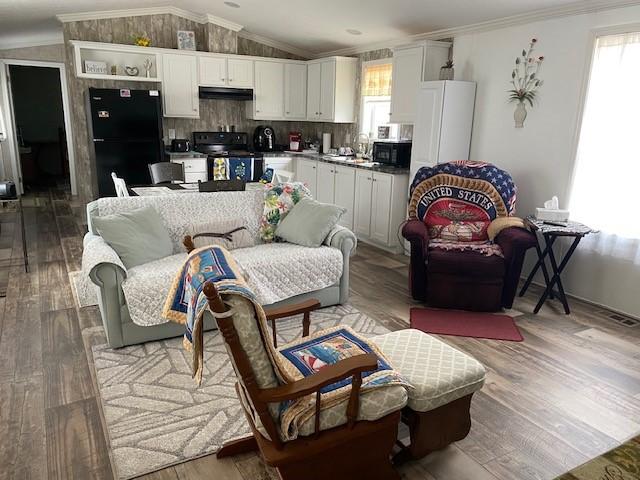 living room with lofted ceiling, wood finished floors, and ornamental molding