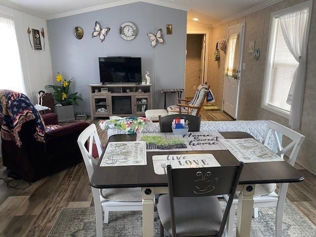 dining space with lofted ceiling, wood finished floors, and crown molding