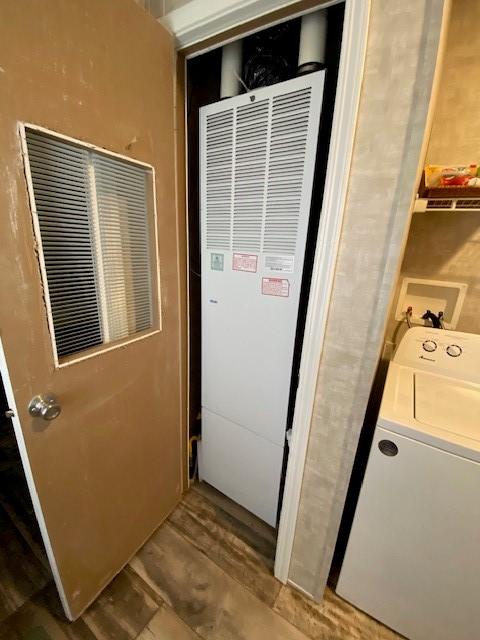 laundry room with laundry area, washer / dryer, a heating unit, and wood finished floors