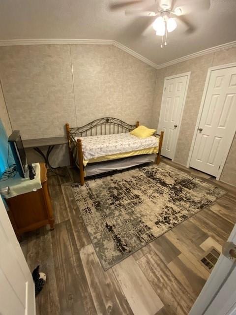 bedroom with ceiling fan, wood finished floors, lofted ceiling, and ornamental molding