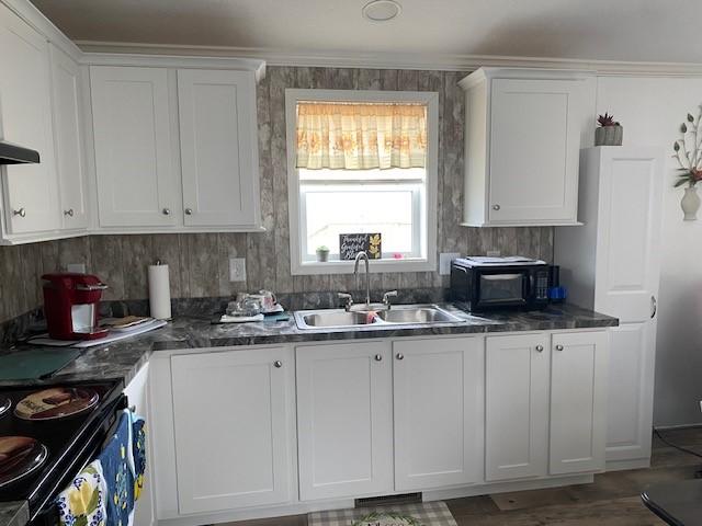 kitchen featuring black appliances, white cabinets, dark countertops, and a sink