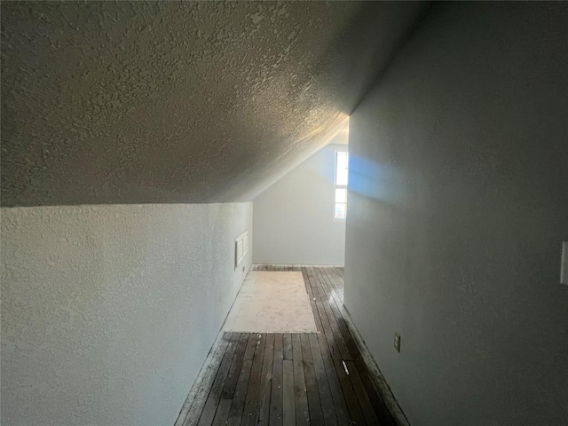 bonus room with a textured ceiling and vaulted ceiling