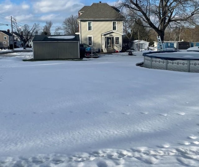 yard layered in snow featuring a storage unit, an outdoor structure, and a hot tub