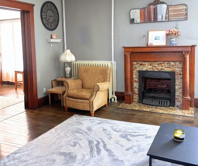 sitting room featuring wood-type flooring, baseboards, and a fireplace with flush hearth