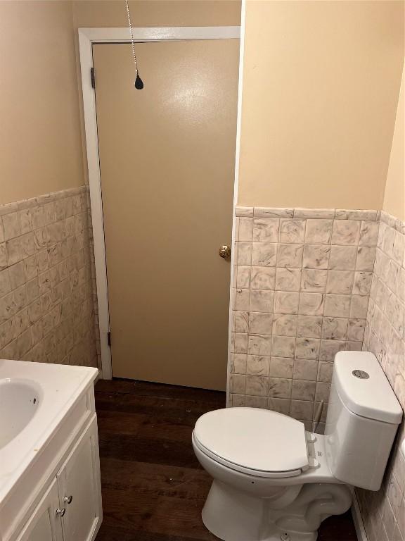 bathroom with tile walls, toilet, wood-type flooring, and vanity