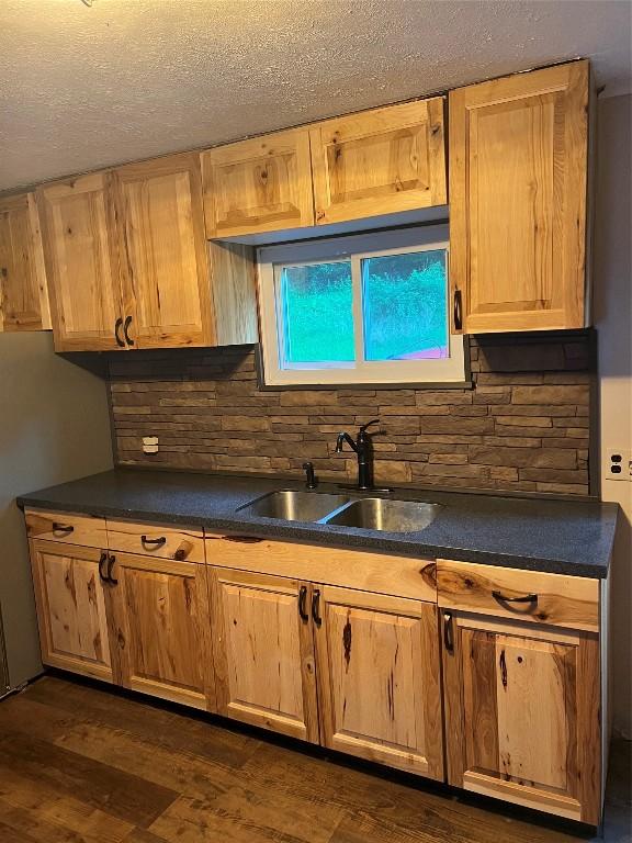 kitchen featuring sink, dark wood-type flooring, backsplash, and a textured ceiling