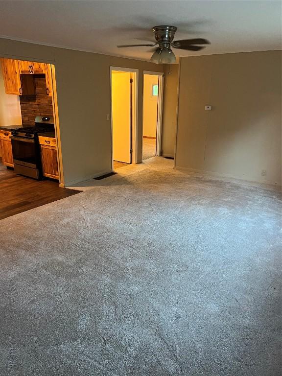 unfurnished living room with ceiling fan and carpet