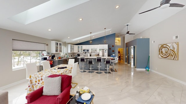 living room with ceiling fan, sink, a skylight, and high vaulted ceiling