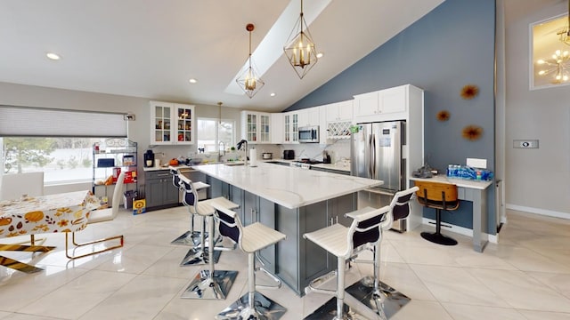 kitchen featuring decorative light fixtures, white cabinets, a kitchen breakfast bar, light stone counters, and stainless steel appliances