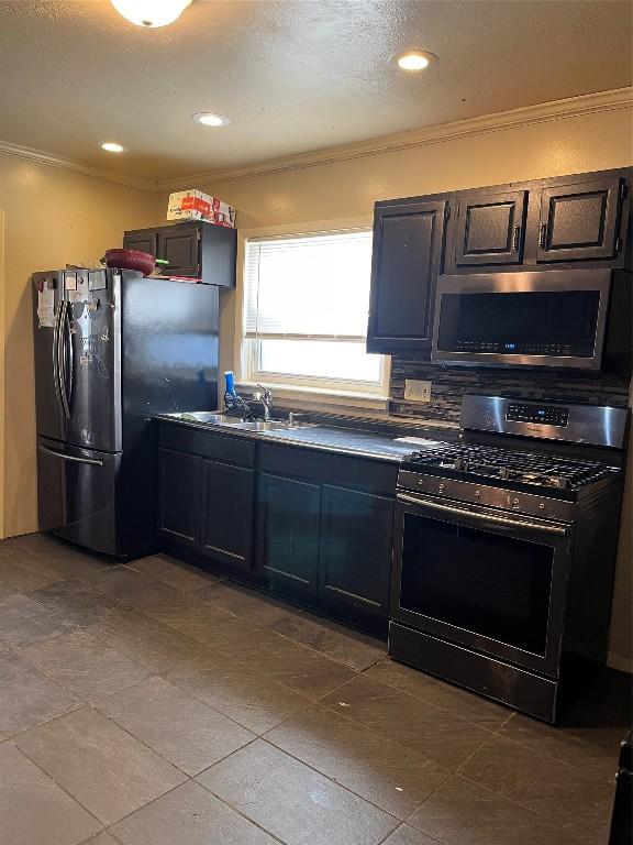 kitchen with appliances with stainless steel finishes, sink, decorative backsplash, crown molding, and a textured ceiling