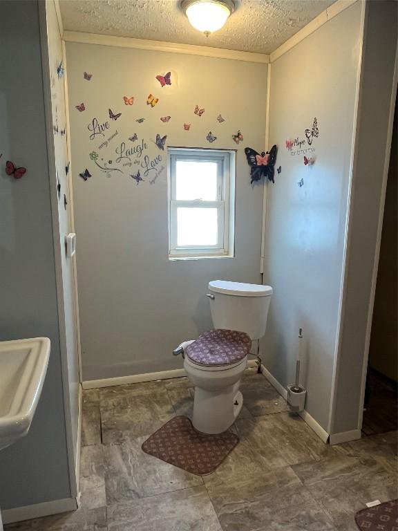 bathroom with crown molding, toilet, and a textured ceiling