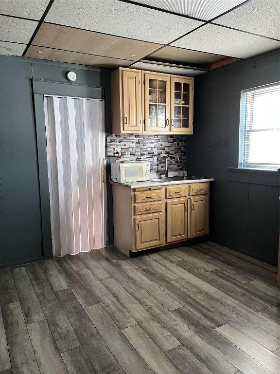 kitchen featuring hardwood / wood-style flooring, light brown cabinetry, tasteful backsplash, and a drop ceiling