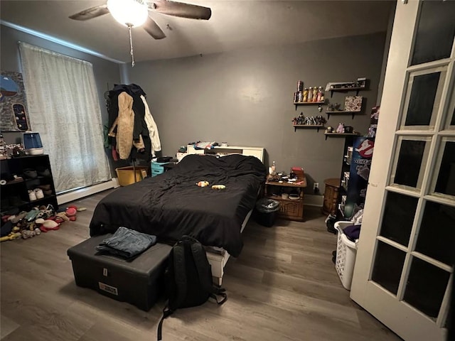bedroom with wood finished floors, a ceiling fan, and a baseboard heating unit