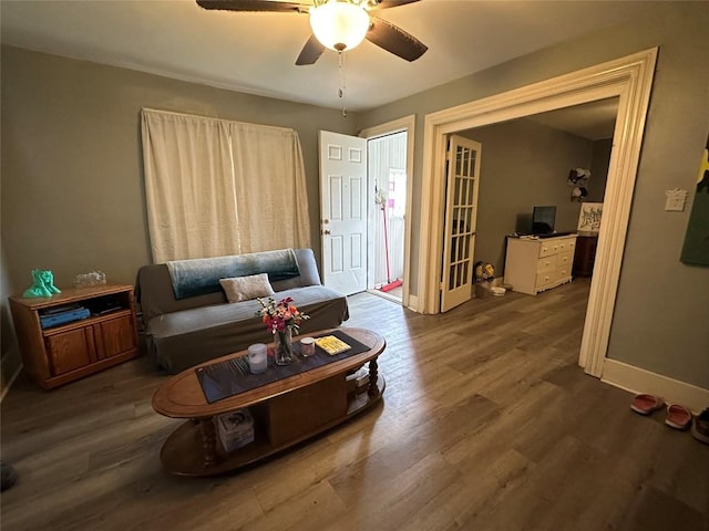 living area featuring baseboards, ceiling fan, and wood finished floors