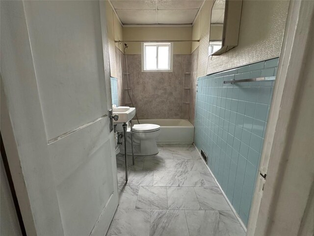 bathroom with tile walls, bathtub / shower combination, toilet, and marble finish floor