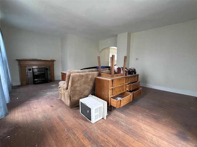 living area with arched walkways, baseboards, hardwood / wood-style flooring, and a fireplace
