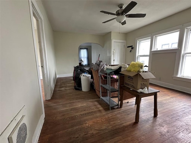 dining area featuring a healthy amount of sunlight, a ceiling fan, arched walkways, hardwood / wood-style flooring, and baseboards