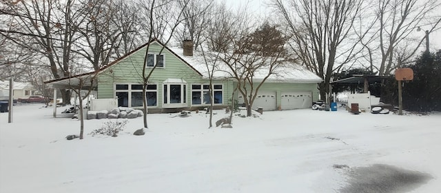 snow covered rear of property with a garage