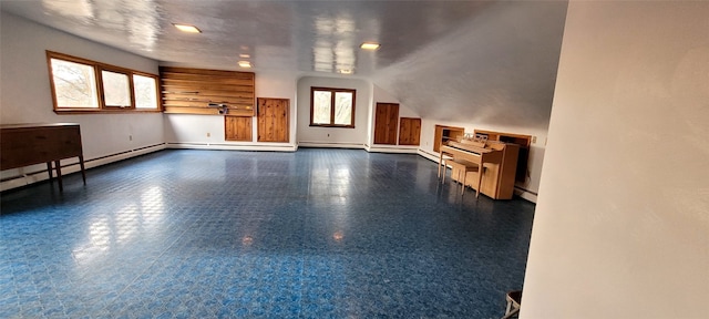 unfurnished living room with a baseboard radiator and vaulted ceiling