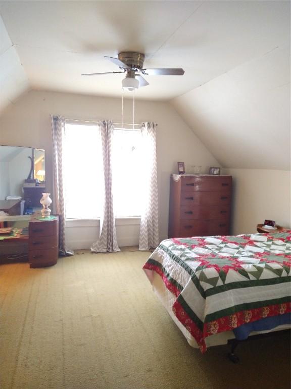 bedroom with lofted ceiling, ceiling fan, and light carpet