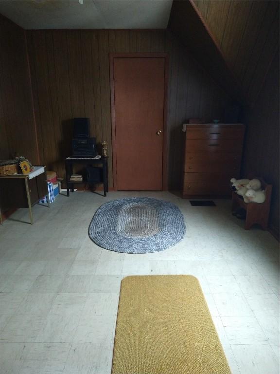 additional living space with lofted ceiling, wood walls, and light floors