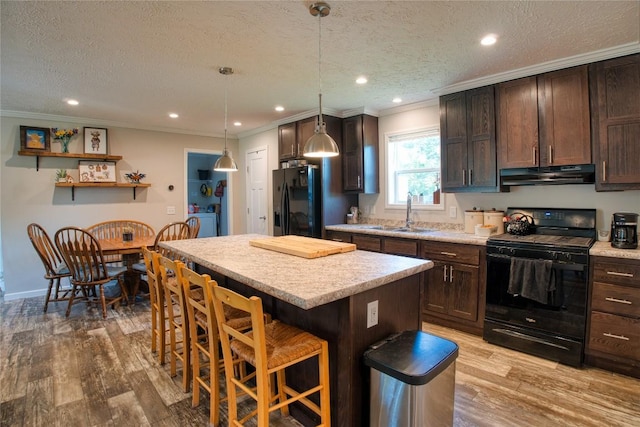 134 Primrose Ln, Edinboro, PA 16412 - kitchen with black appliances, under cabinet range hood, dark brown cabinets, ornamental molding, and a kitchen breakfast bar