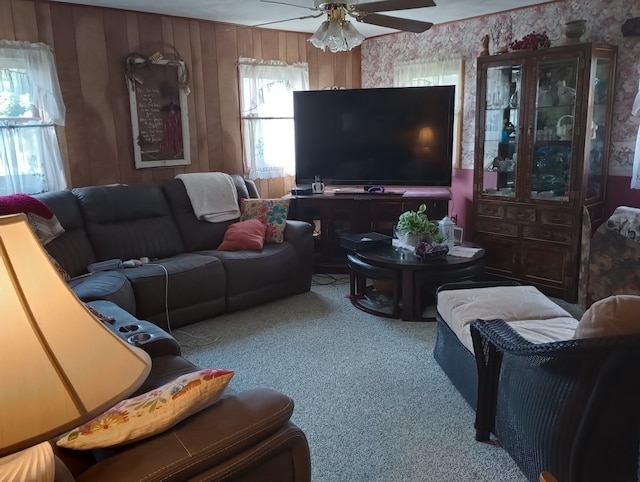 carpeted living room featuring ceiling fan and wood walls