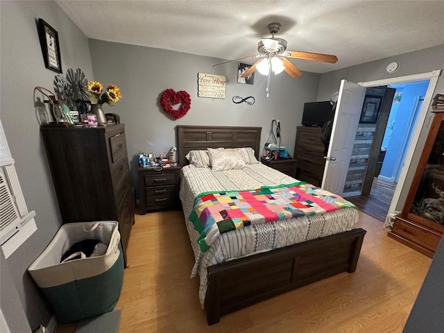 bedroom with a textured ceiling, light wood-type flooring, and ceiling fan