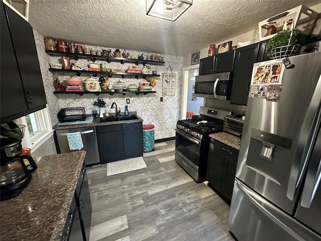 kitchen with a textured ceiling, light hardwood / wood-style floors, sink, and appliances with stainless steel finishes