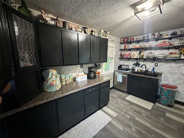 kitchen featuring dishwasher, a textured ceiling, dark stone countertops, and sink