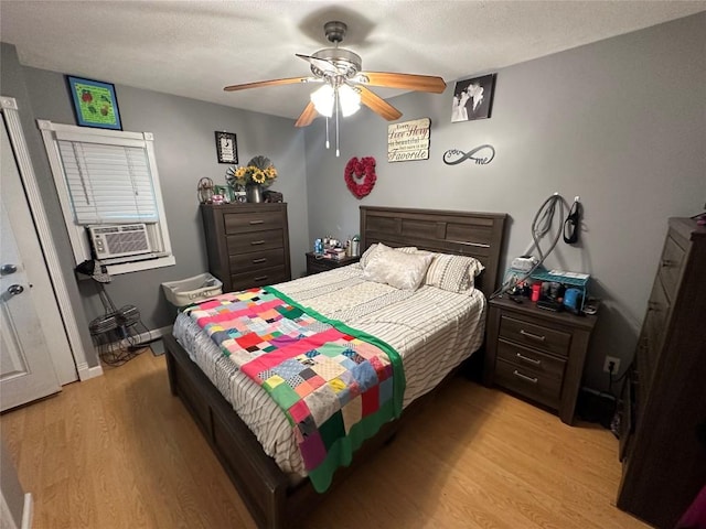 bedroom with ceiling fan, cooling unit, light hardwood / wood-style floors, and a textured ceiling