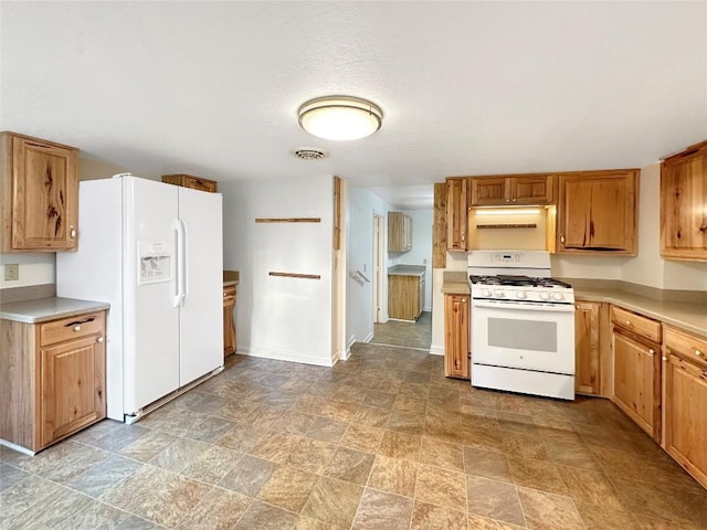 kitchen with visible vents, light countertops, white appliances, and stone finish floor