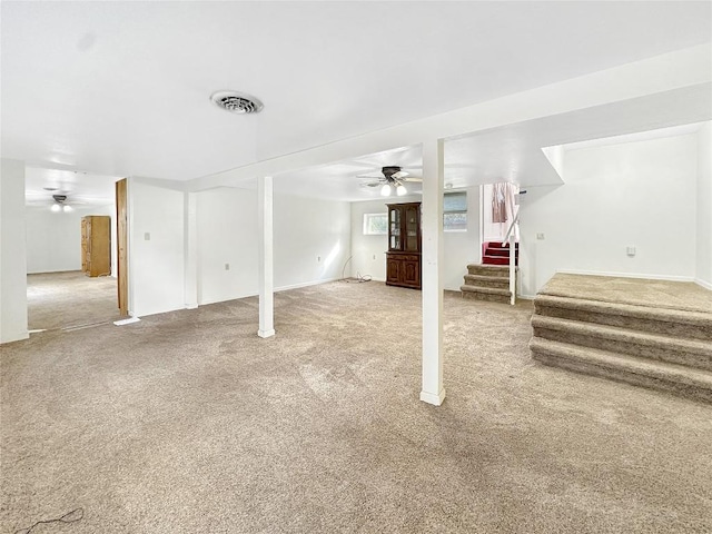 below grade area featuring stairway, carpet flooring, visible vents, and ceiling fan