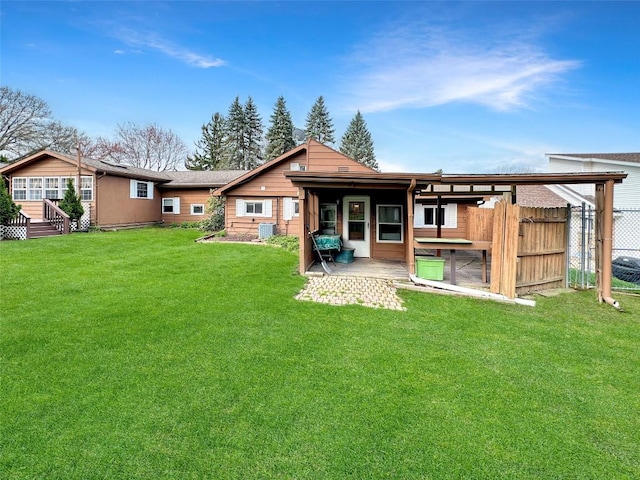 rear view of property featuring central air condition unit, a lawn, and fence
