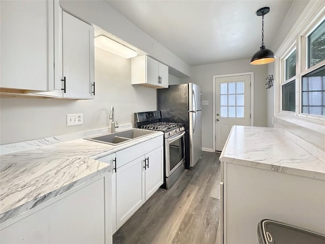 kitchen with decorative light fixtures, white cabinetry, sink, hardwood / wood-style flooring, and stainless steel appliances