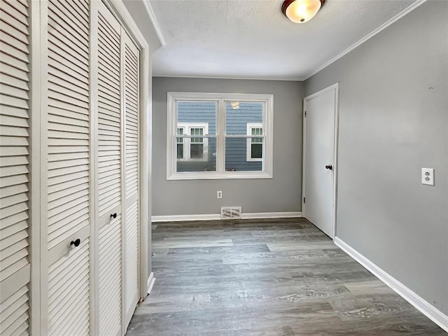 unfurnished bedroom with dark wood-type flooring, ornamental molding, a closet, and a textured ceiling