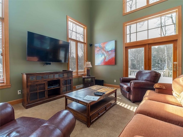 living room featuring a towering ceiling and light carpet