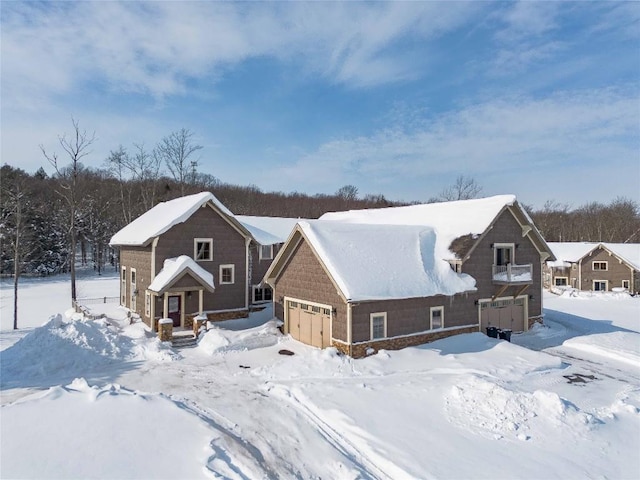 snow covered back of property featuring a garage