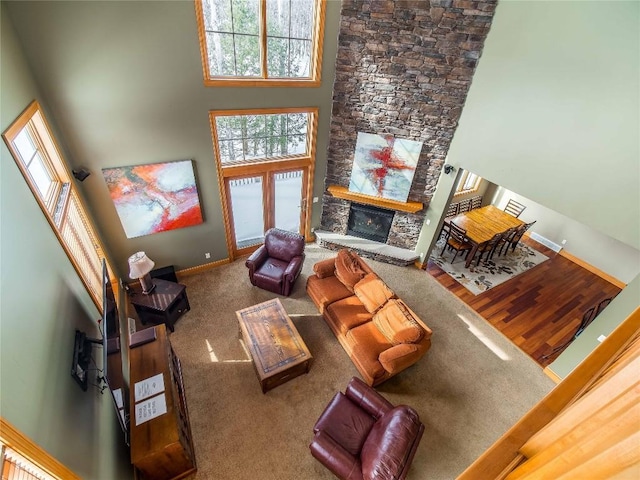 living room featuring a towering ceiling, a stone fireplace, and carpet