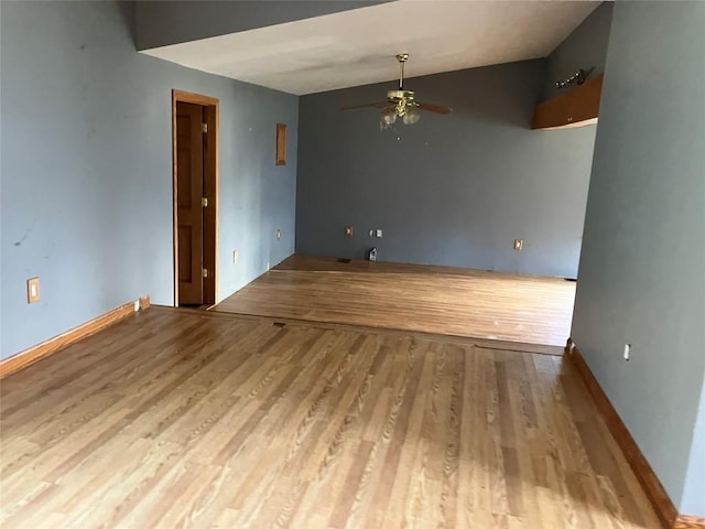 spare room with a ceiling fan, wood finished floors, lofted ceiling, and baseboards