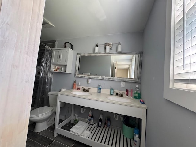full bath with a shower with shower curtain, wood finish floors, a sink, and toilet
