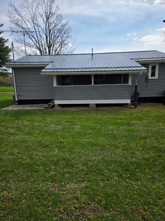 back of property with a lawn and metal roof