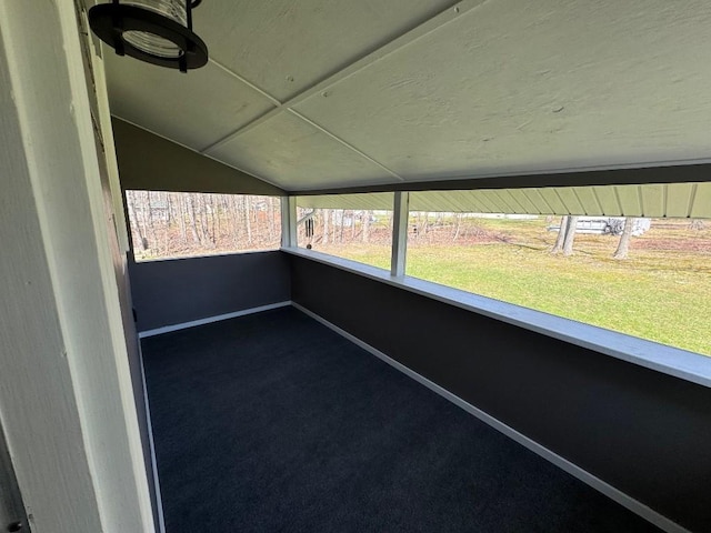 unfurnished sunroom with baseboards, carpet, and lofted ceiling